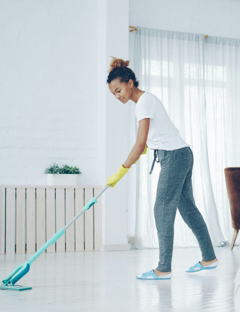 A cleaner mopping the floor of a bright apartment